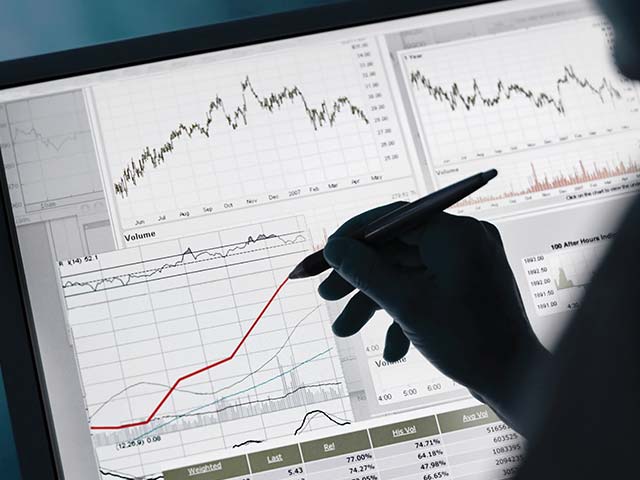 Person using a stylus on a tablet with financial graphs and charts displayed on the screen.