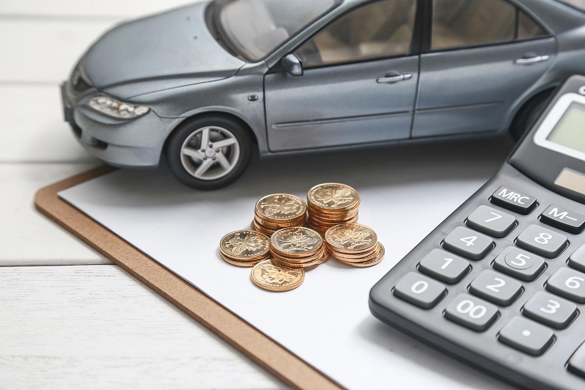 Car model, stacked coins, and a calculator on a clipboard, symbolizing car expenses or budgeting.
